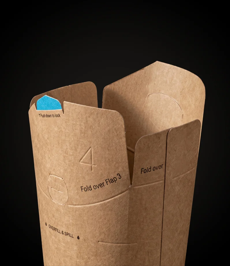Nahaufnahme eines deckellosen Bechers aus Kraftpapier mit geöffneten, bedruckten Faltlaschen, die die nummerierte Faltfolge am Rand zeigen.